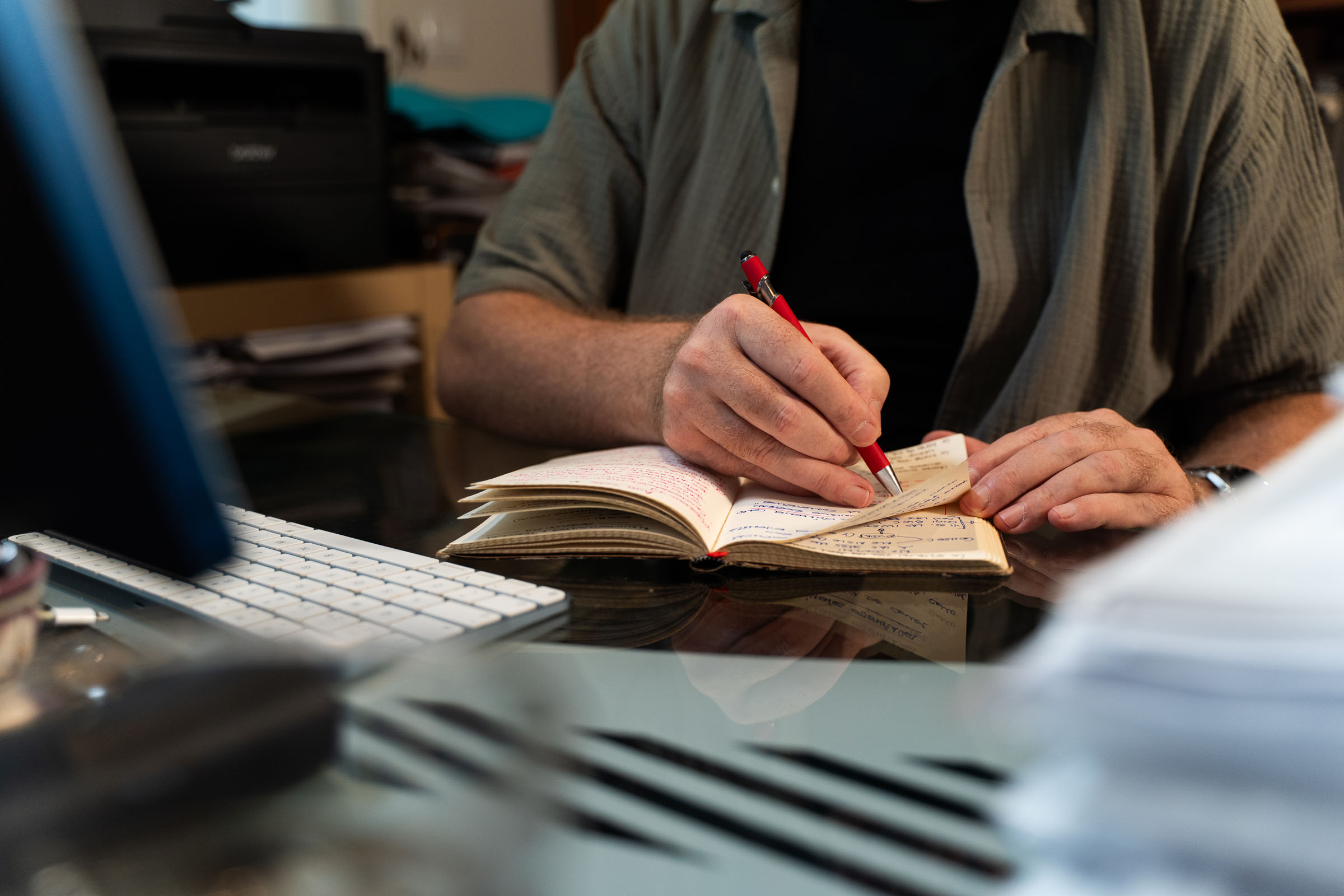 Manos de Poti de Cai escribiendo en un cuaderno junto a sus materiales de trabajo